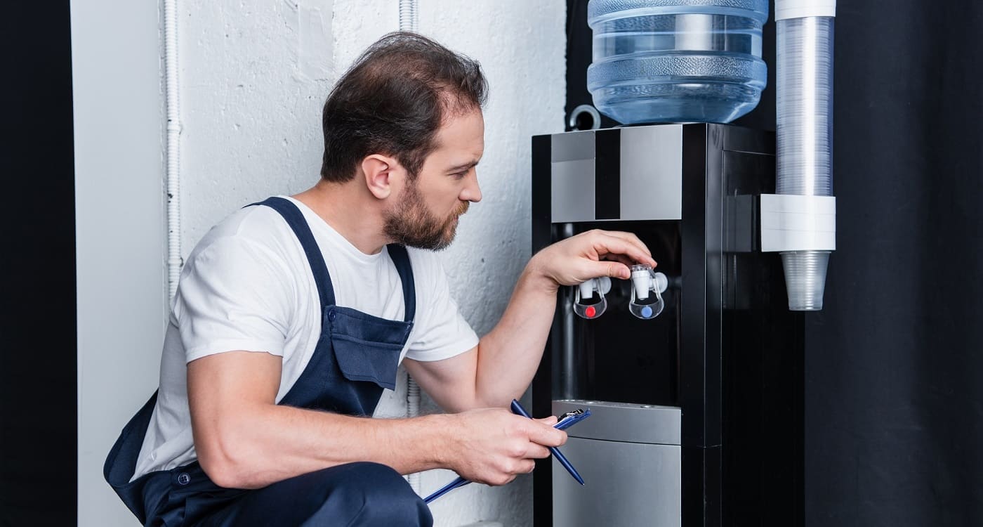 Mitarbeiter einer Firma für Wasserspender beim Einrichten eines Wasserspenders in einem Büro